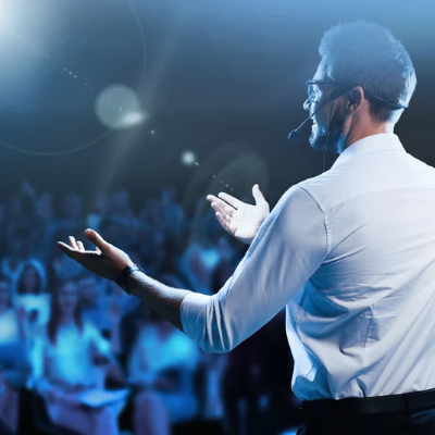 Confident person speaking to an audience, representing personal growth through public speaking coaching and hypnotherapy
